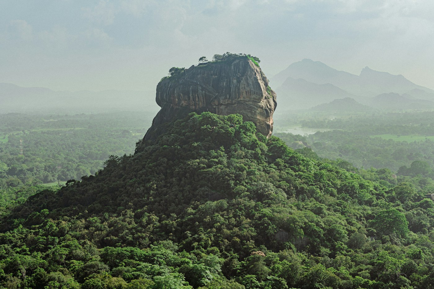 Sigiriya rock rising above misty forest